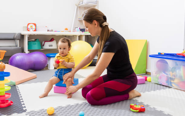 istock Physiotherapist assisting a little child with coordination disorders during motor skills development exercise in modern rehab clinic. Physiotherapy 2161574794