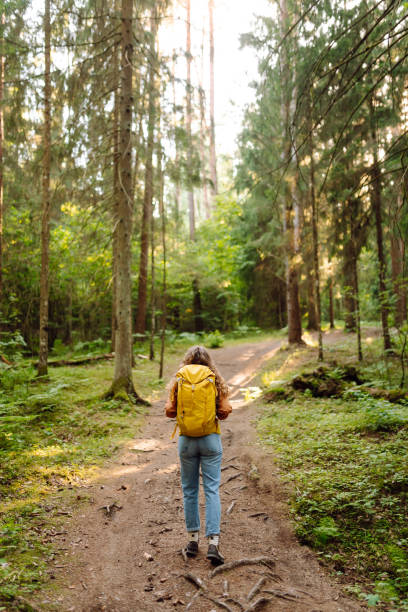 istock Woman tourist yellow backpack hiking in spring forest 2161576623