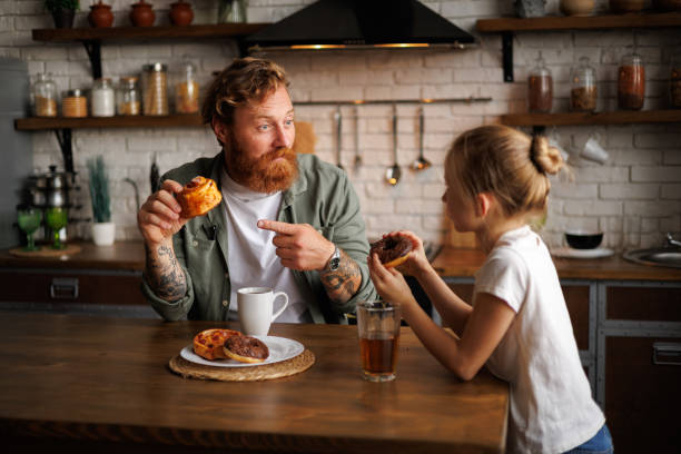 istock Tattooed father pointing at pastry near daughter and drinks during breakfast in kitchen 2161580862