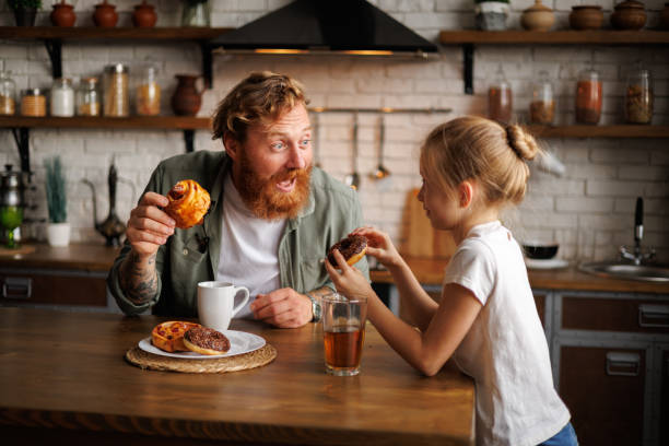 istock Excited dad having fun with daughter during breakfast with sweet pastry and drinks in kitchen 2161580869