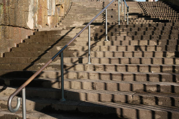 Old concrete staircase with metal handrail and shadow pattern..