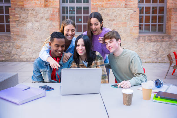 istock A group of students with laptops sit near the campus and communicate. 2161585138