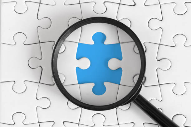 istock Magnifying Glass Highlights Missing Puzzle Piece on Blue Background 2161589352