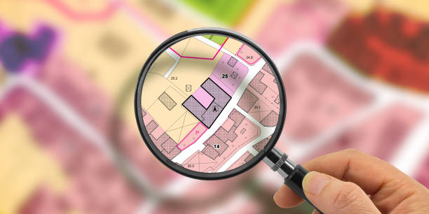 istock FIND VACANT LAND FOR BUILDING ACTIVITY AND HOME DEVELOPMENT - Concept with magnifying glass on cadastral map to find the plots of land - Building roject concept 2161592241
