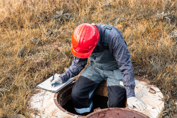 istock A worker in a helmet records meter readings while sitting on a water well. Plumbing inspection and maintenance 2161606320