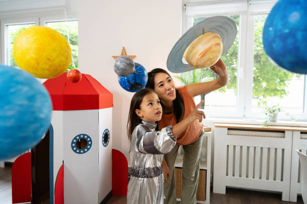 istock Girl in a space suit exploring and learning about planets with her mother 2161612620