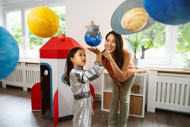 istock Girl in a space suit exploring and learning about planets with her mother 2161612627