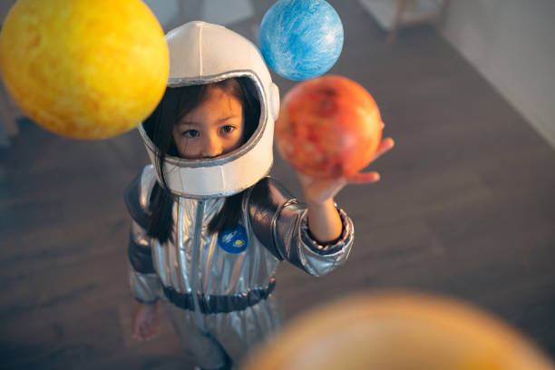 istock Girl in a space suit playing at home, exploring and learning about planets, imagining space travel. 2161612674