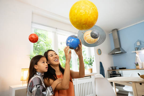istock Girl in a space suit exploring and learning about planets with her mother 2161612700