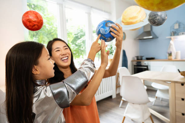istock Girl in a space suit exploring and learning about planets with her mother 2161612710