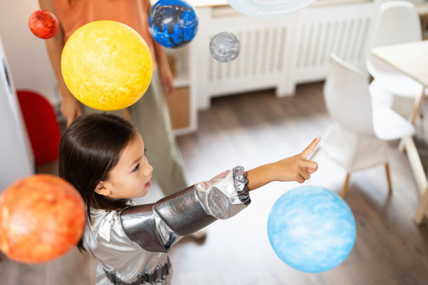 istock Girl in a space suit exploring and learning about planets with her mother 2161612802