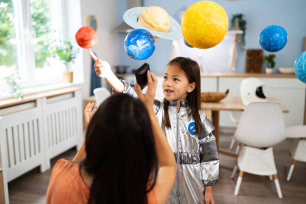 istock Girl in a space suit exploring and learning about planets with her mother 2161612844