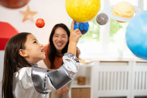 istock Girl in a space suit exploring and learning about planets with her mother 2161612848