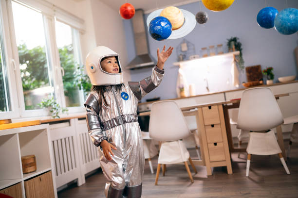 istock Girl in a space suit playing at home, exploring and learning about planets, imagining space travel. 2161613017