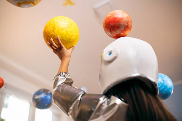 istock Girl in a space suit playing at home, exploring and learning about planets, imagining space travel. 2161613019