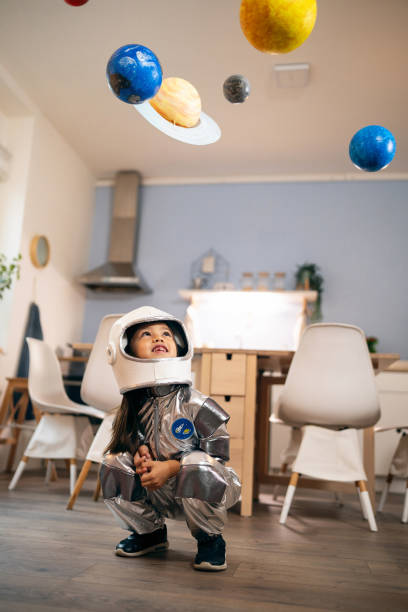 istock Girl in a space suit playing at home, exploring and learning about planets, imagining space travel. 2161613079