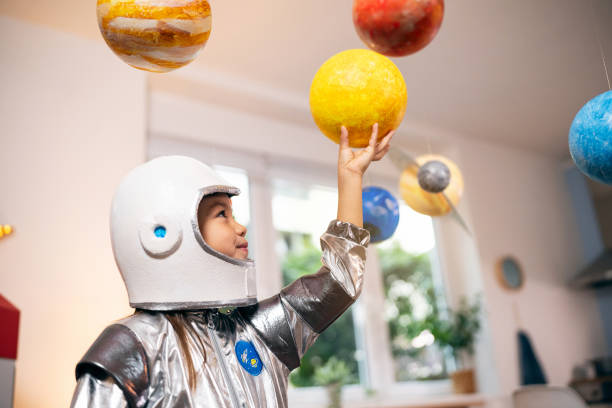 istock Girl in a space suit playing at home, exploring and learning about planets, imagining space travel. 2161613085