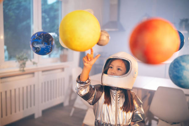 istock Girl in a space suit playing at home, exploring and learning about planets, imagining space travel. 2161613805