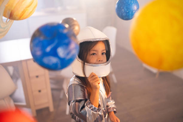 istock Girl in a space suit playing at home, exploring and learning about planets, imagining space travel. 2161613898