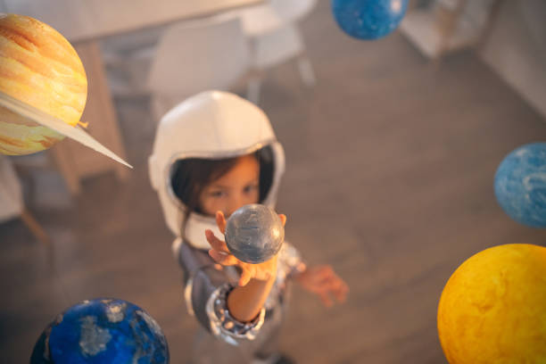 istock Girl in a space suit playing at home, exploring and learning about planets, imagining space travel. 2161613954