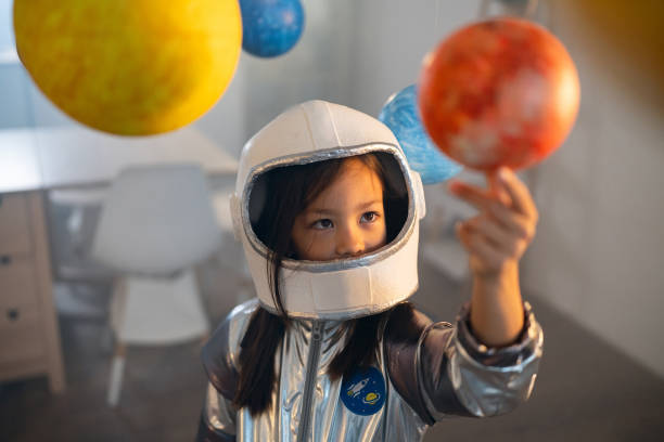 istock Girl in a space suit playing at home, exploring and learning about planets, imagining space travel. 2161613955