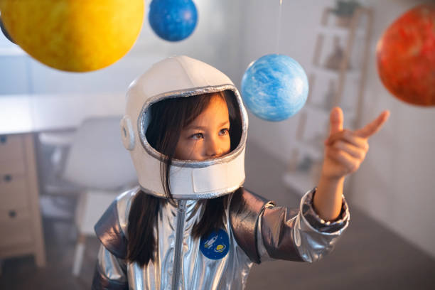 istock Girl in a space suit playing at home, exploring and learning about planets, imagining space travel. 2161613956