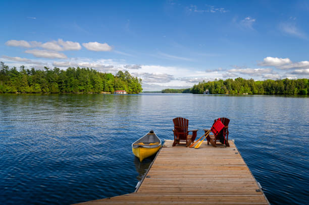istock Adirondack chairs and canoe on a cottage dock 2161615416