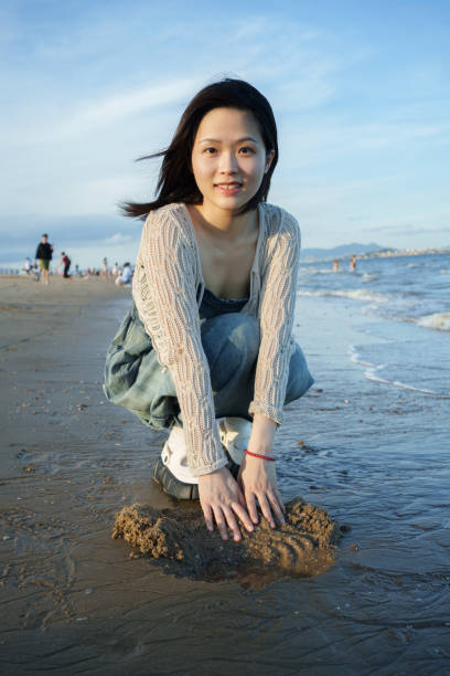 istock girl squatting on the beach 2161617946