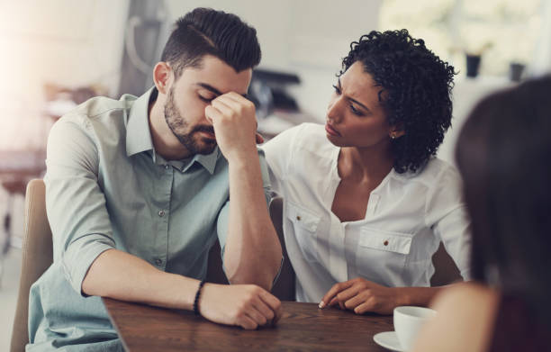 istock Couple, comfort and man with support in stress for counseling, compassion or advice on problem. Frustrated, person and woman with therapy by table for cheating mistake, regret or kindness in bad news 2161632380