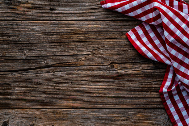 Flat lay of an empty rustic wooden table with checkered tablecloth at the border