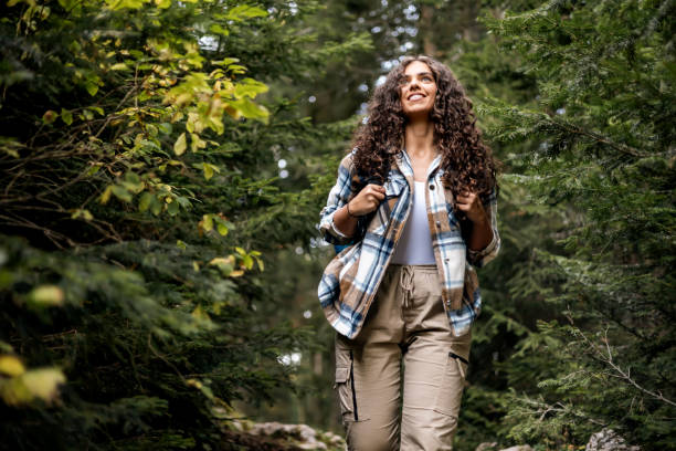 istock Smiling woman hiking in lush forest with backpack on 2161634365