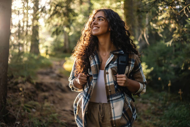 Cheerful woman hiking on forest path with backpack