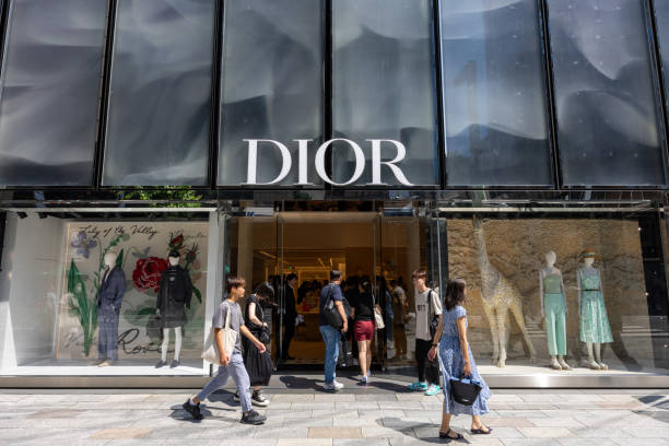 Detailed view of Dior Gold House behind trees in Bangkok downtown. Seen from opposite side of street Phloen Chit Road  in Bangkok downtown.  It is located at Phloen Chit Rd. in Bangkok Lumpini, Pathum Wan,  downtown. Building has golden facade and is  a tourist attraction