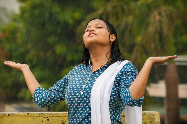 Portrait of happy indian young woman enjoying the rain. Portrait of happy indian young woman in traditional wear stretched her arm enjoying monsoon rain. soaked suit stock pictures, royalty-free photos & images