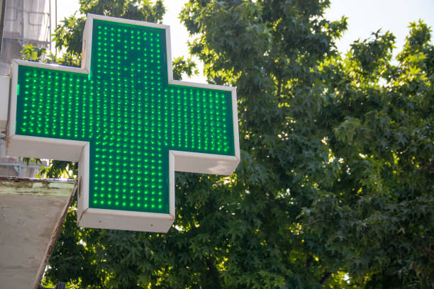istock Pharmacy indication sign, a luminous green cross that indicates that a pharmacy is open and providing service. 2161650681