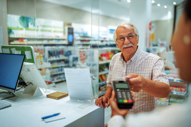 Senior man paying with credit card at pharmacy store