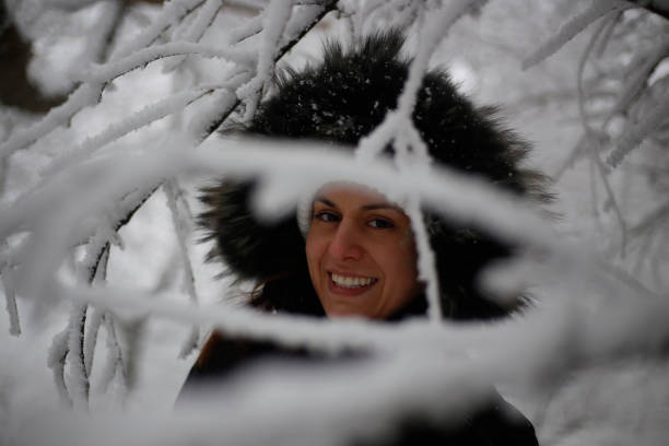 Smiling woman wearing scarf in a winter cold day. Happy girl in a sweater outdoor in snow. Beautiful smiling woman with hat and scarf outdoor looking away.
