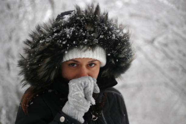Smiling woman wearing scarf in a winter cold day. Happy girl in a sweater outdoor in snow. Beautiful smiling woman with hat and scarf outdoor looking away.