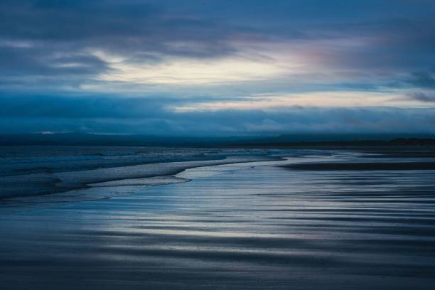 istock Serene beach at dusk with reflective water and a cloudy sky 2161660852