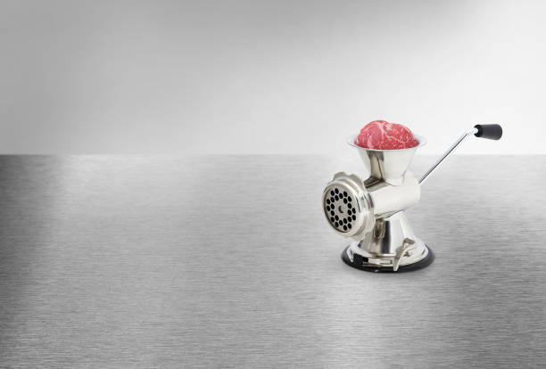 Metal hand meat grinder on a metal table