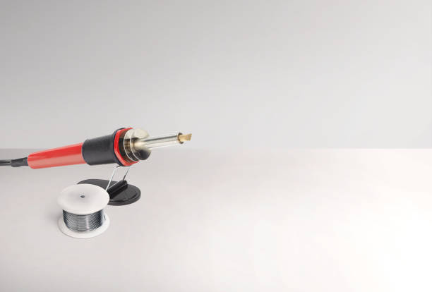 Soldering iron on a stand with soldering electrical wire on a white background