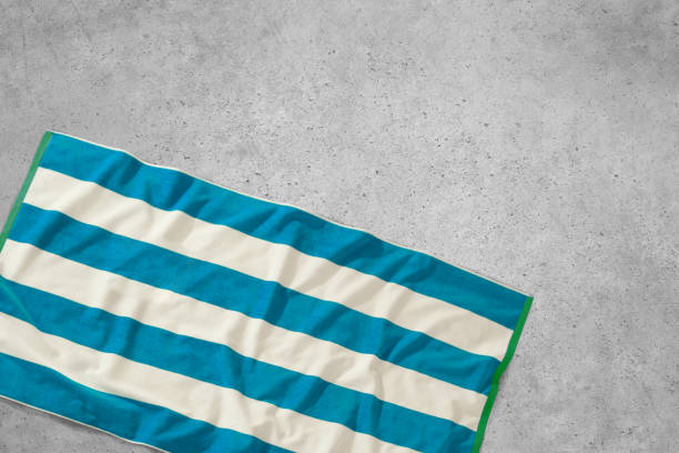 Stripped blue and white beach towel on a concrete surface