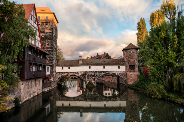 The famous Nuremberg Hangman’s Bridge was built in 1595 when Nuremberg suffered severe damage from a flood. The previous bridge, built in 1457 and part of the city wall, was badly damaged. It was therefore replaced by the wooden bridge with bricks. The unusual name of the Hangman’s Footbridge comes from the neighbouring tower, where the hangman of Nuremberg lived between the 16th and 19th centuries. In the Middle Ages, the hangman entered the city via the Henkersteg. During the Second World War, the wooden footbridge was again badly damaged. It was not until 1954 that it was rebuilt to its original design.