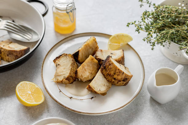 Whole roasted celery root with sauce on a plate Roasted celeriac slices served on a plate with tahini honey lemon sauce and thyme Celeriac stock pictures, royalty-free photos & images