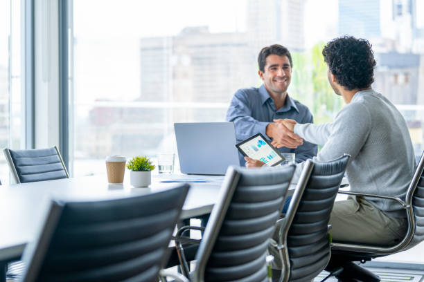 istock Two businessmen working on a digital tablet and laptop computer in the office in a board room or meeting room 2161678247