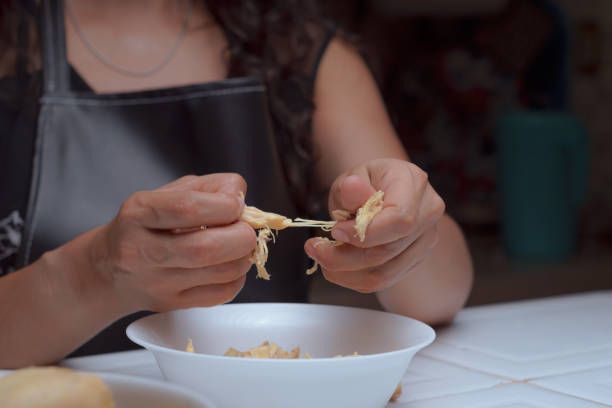 Hands of a chef preparing boiled chicken, shredding chicken