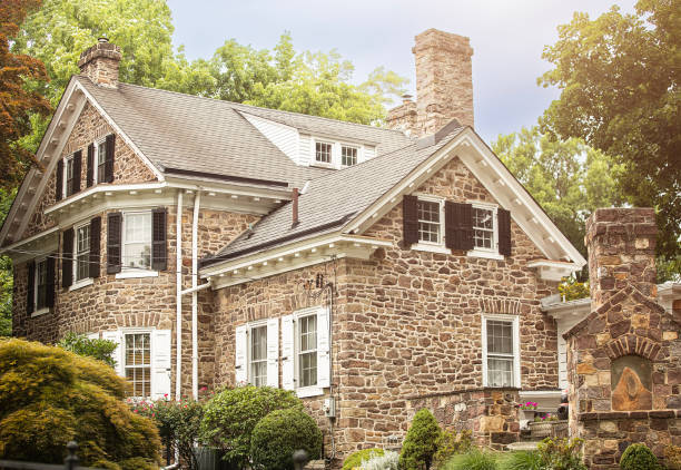 Lambertville, New Jersey, June 30, 2024: A charming stone house is nestled among lush greenery with a well-maintained garden in the foreground. The elegant design features black shutters and white-trimmed windows, giving it a classic and inviting look.