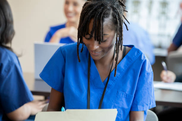 istock a nursing student in blue scrubs focuses on note taking during a classroom lecture. 2161684793