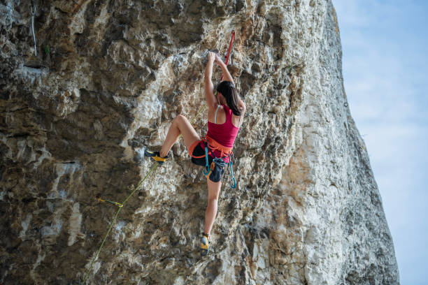 istock Young woman rock climbing on a steep cliff. 2161685811