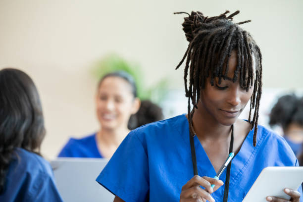 istock With focused determination, a nursing student in blue scrubs prioritizes note-taking as she absorbs the classroom material. 2161686376